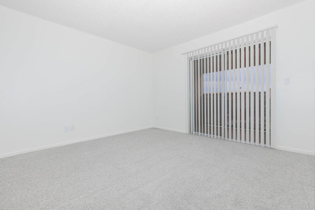 A room with a window covered by vertical blinds.