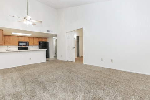 A room with a carpeted floor and a ceiling fan.