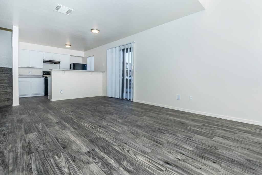 A spacious room with wooden flooring and white walls.