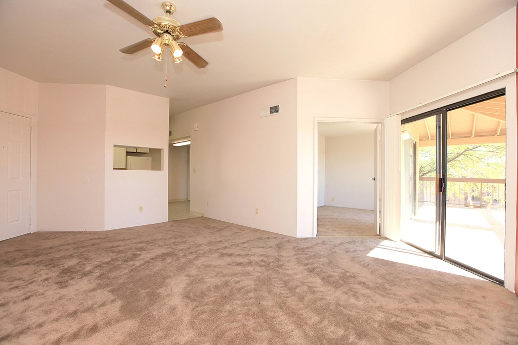 Empty room with a ceiling fan and carpeted floor.