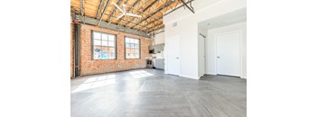 A large empty room with a brick wall and wooden ceiling.