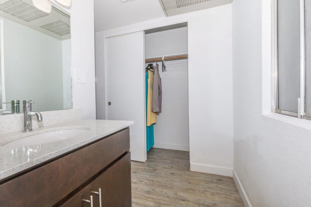 A bathroom with a sink, mirror, and wooden floor.