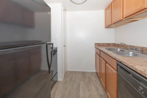 A kitchen with a refrigerator, oven, and sink.