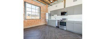 A kitchen with a brick wall and stainless steel appliances.