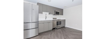 A modern kitchen with stainless steel appliances and wooden flooring.
