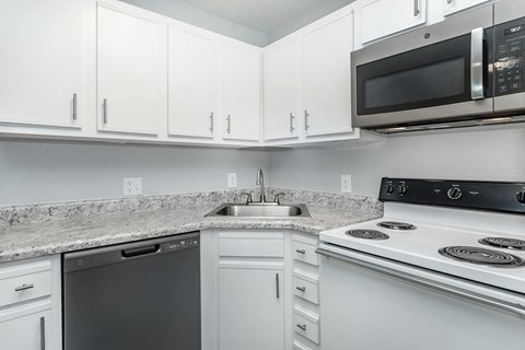 A kitchen with white cabinets and a granite countertop.