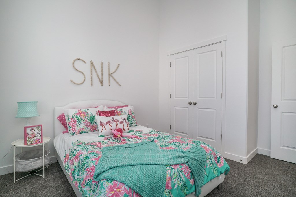 a bedroom with a bed with a tropical bedspread and a bedside table with a lamp