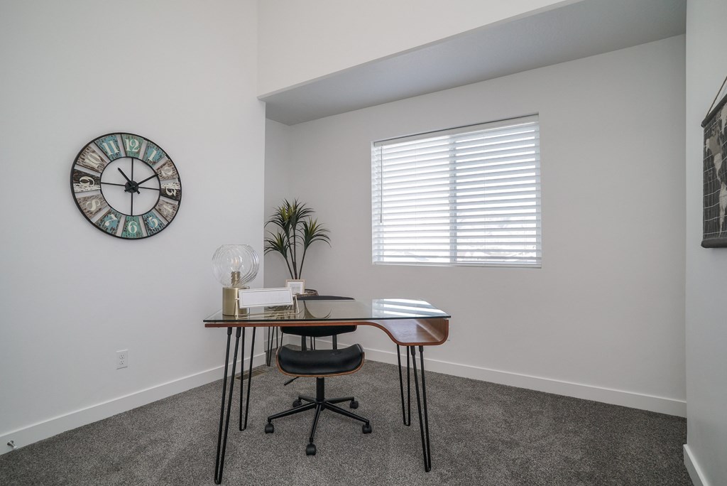 a small desk in a corner of a room with a large clock on the wall