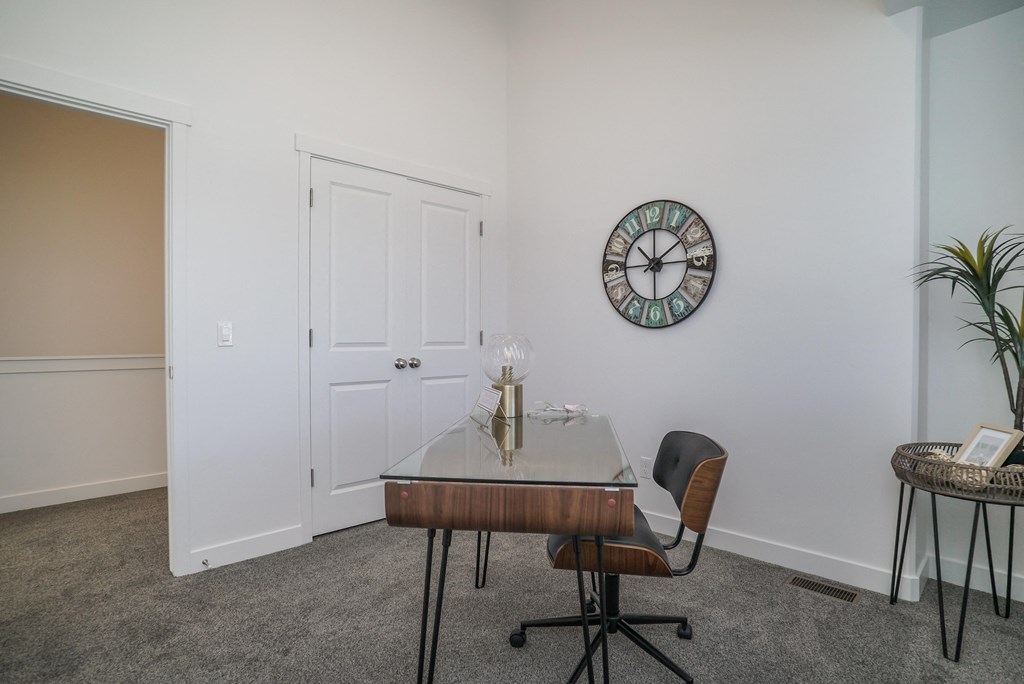 a desk with a glass top in a room with a clock on the wall
