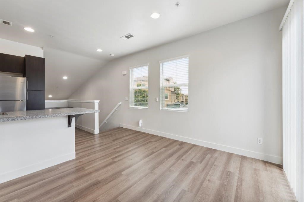 the living room and kitchen of a house with white walls and wood floors