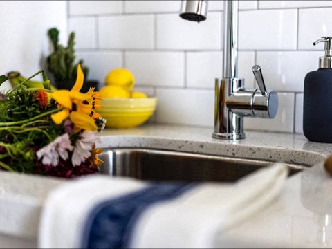 a kitchen sink with a bowl of lemons in the background