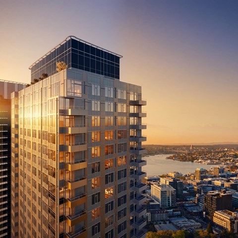 A modern glass building stands tall against a cityscape at sunset.