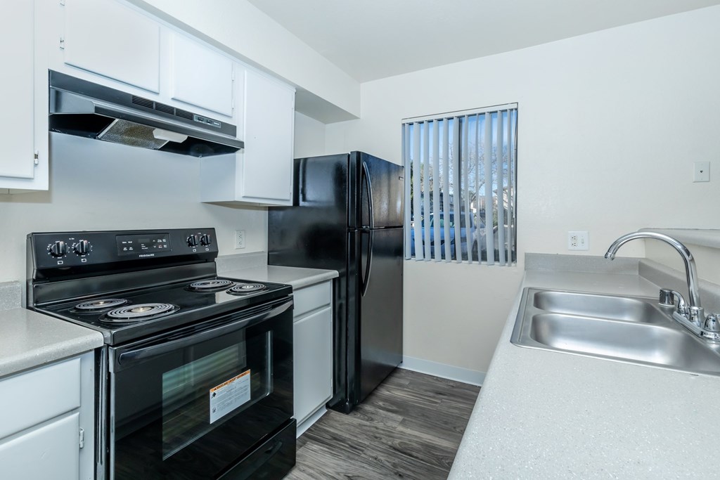 A black stove and refrigerator in a white kitchen.