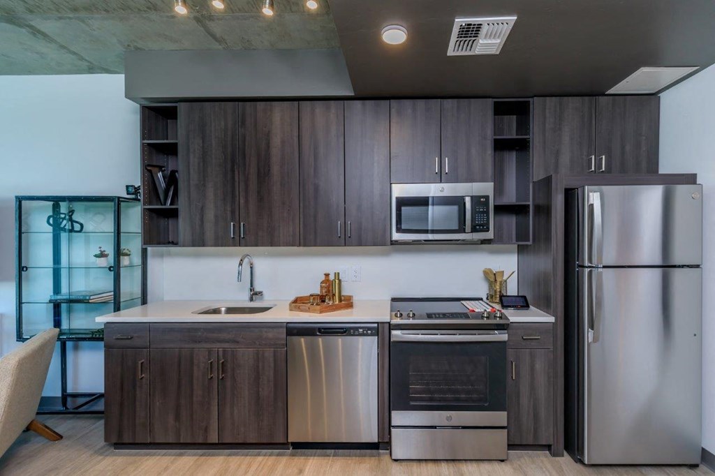 A modern kitchen with dark wood cabinets and stainless steel appliances.