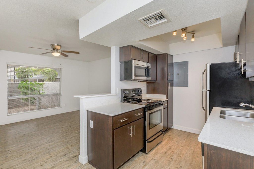 A kitchen with a black refrigerator and wooden floors.