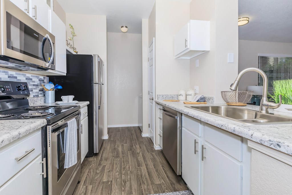 A kitchen with a black refrigerator and stove top oven.