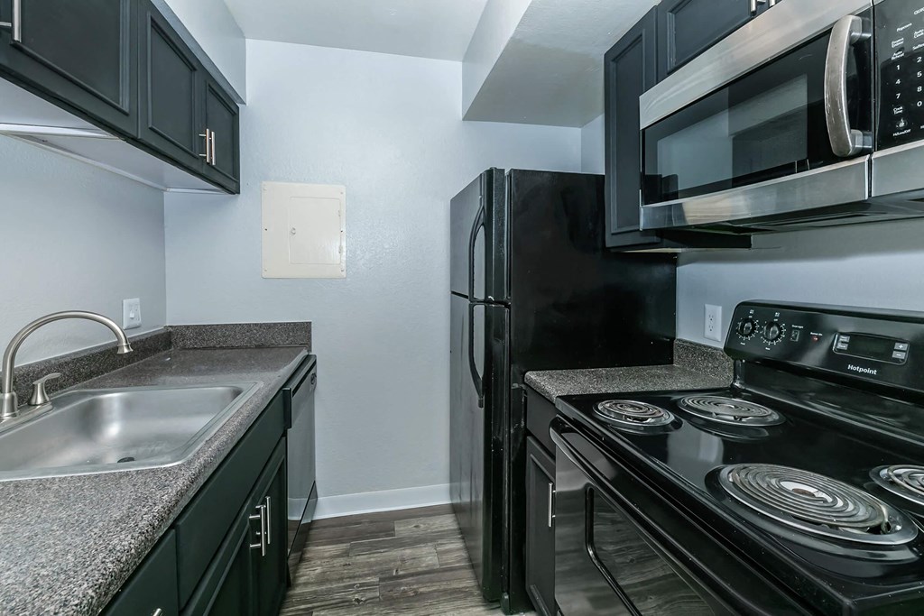 A black refrigerator and microwave in a kitchen.