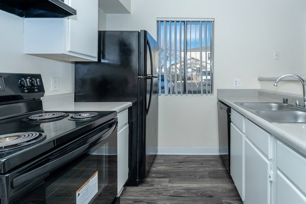 A black stove top oven sits next to a black refrigerator in a kitchen.