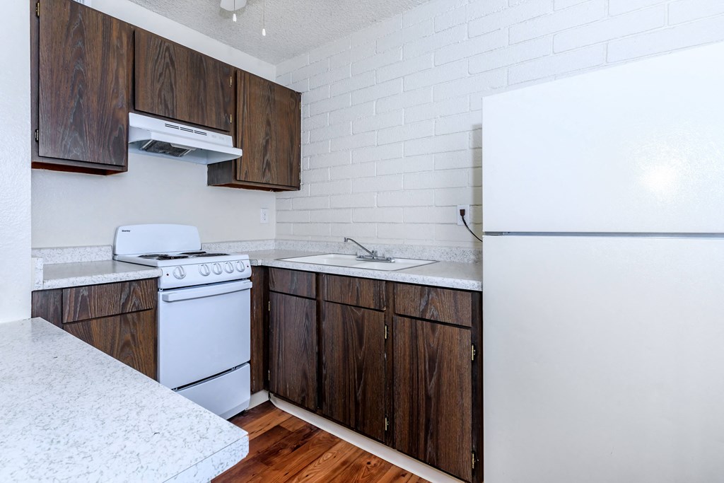 A kitchen with white appliances and wooden cabinets.