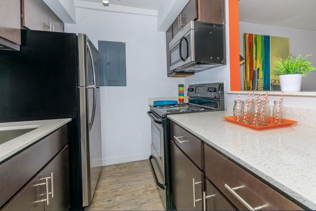 A kitchen with a black fridge, microwave, and stove.