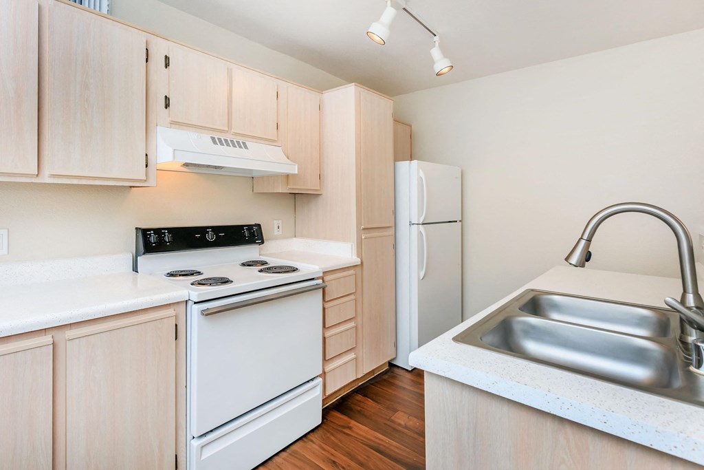 A kitchen with a white stove, refrigerator, and wooden cabinets.