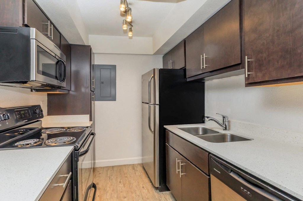 A kitchen with black appliances and brown cabinets.