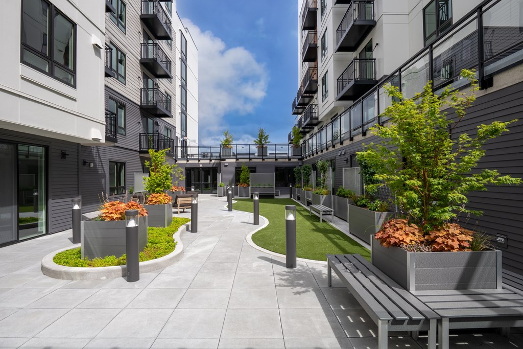 A modern outdoor residential area with benches and planters.