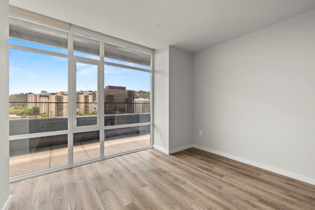 an empty living room with a large window and wood floors