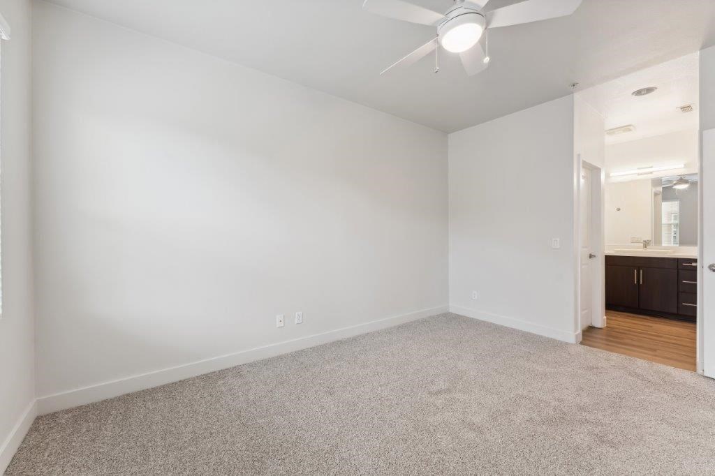 an empty living room with white walls and a ceiling fan