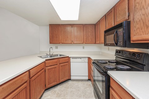 A kitchen with wooden cabinets and a black microwave above the stove.