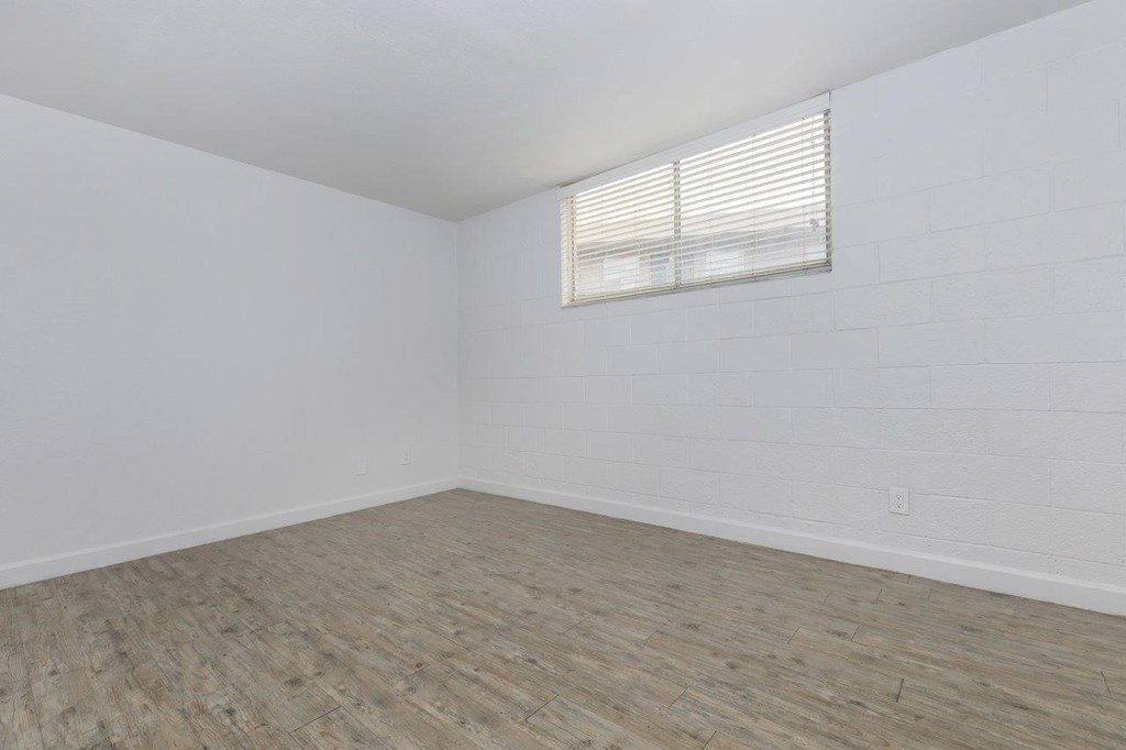A room with wooden flooring and a window with blinds.
