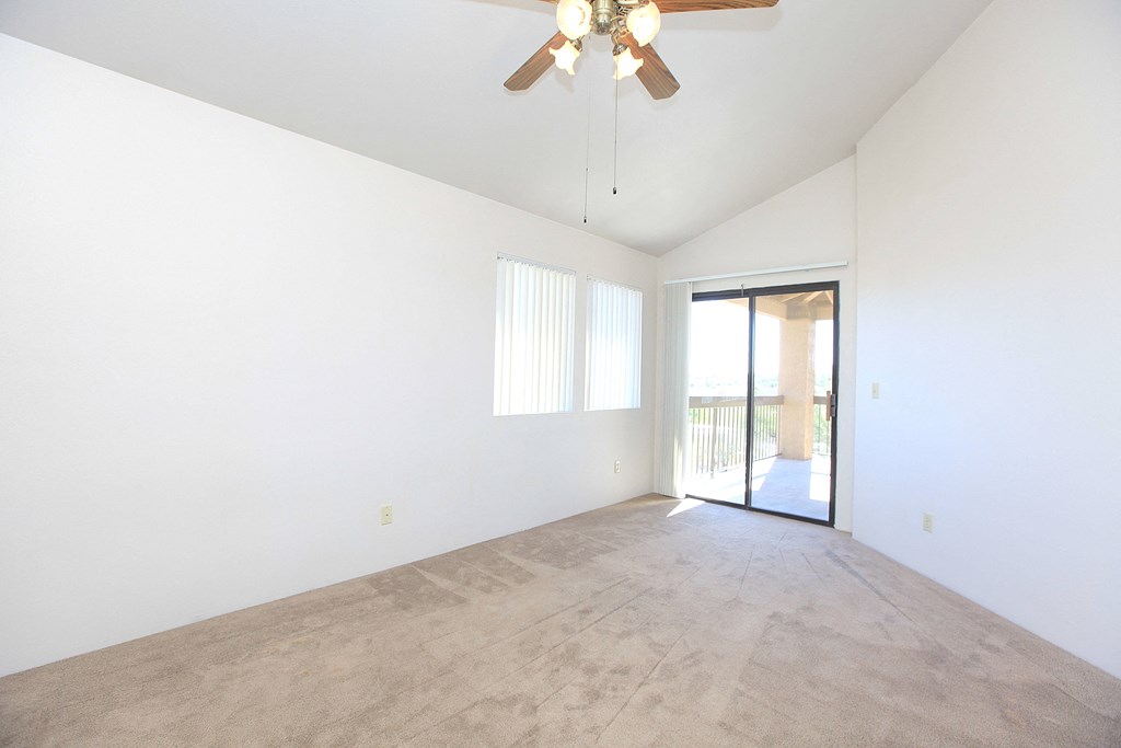 A room with a ceiling fan and carpeted floor.