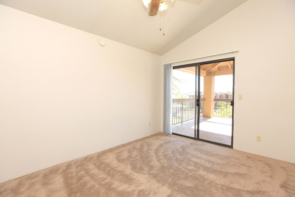A room with a carpeted floor and a sliding glass door leading outside.