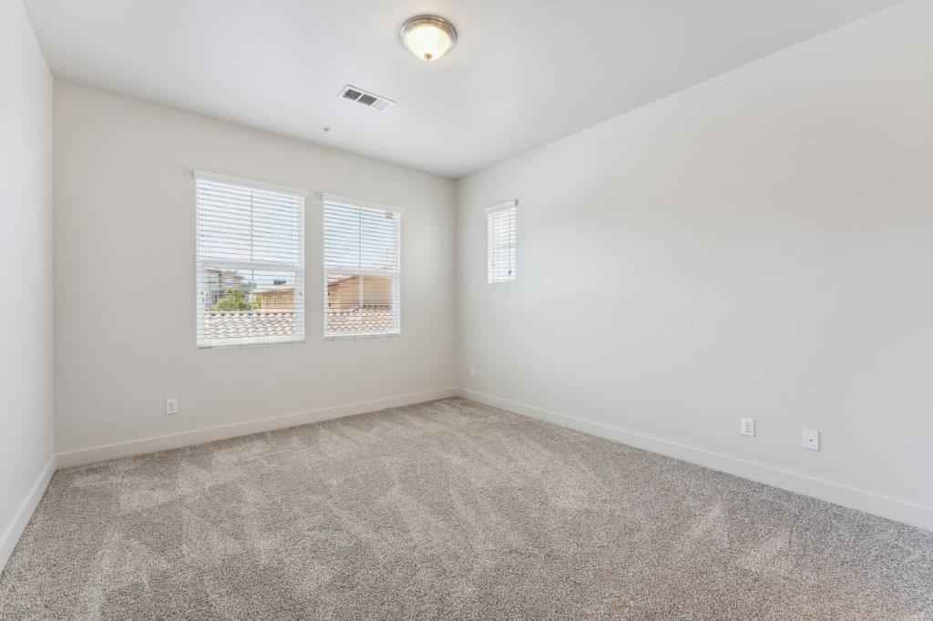 an empty living room with two windows and carpet