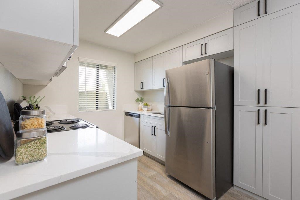 a white kitchen with a stainless steel refrigerator