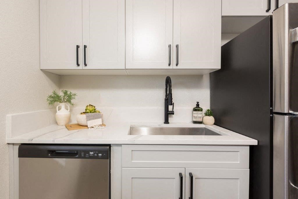 a white kitchen with white cabinets and a black dishwasher
