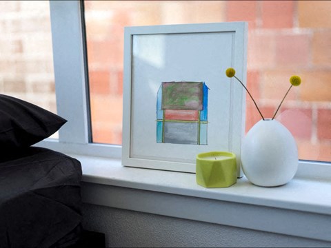 a painting sitting on top of a window sill next to a vase