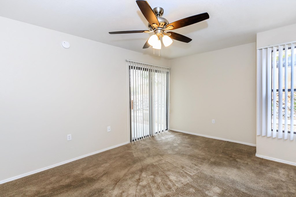 A room with a ceiling fan and carpeted floor.