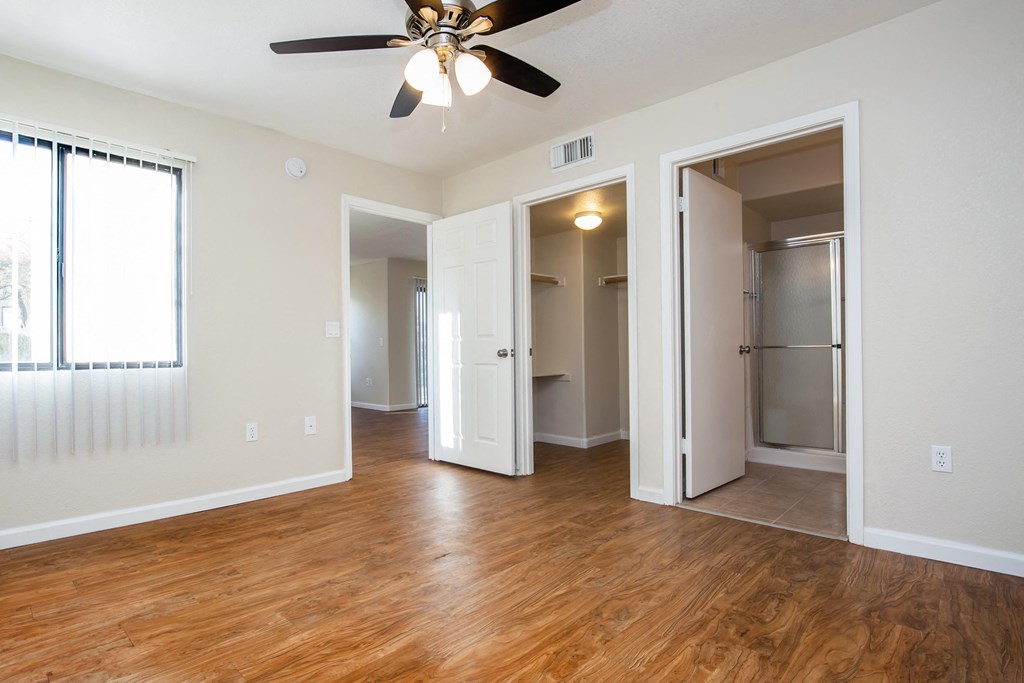 A room with a ceiling fan and wooden floors.