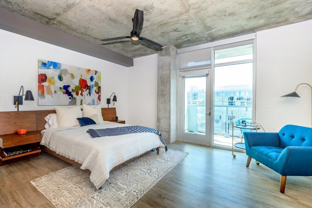 A bedroom with a bed, a chair, and a painting on the wall.