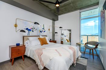 A bedroom with a bed, chair, and a ceiling fan.