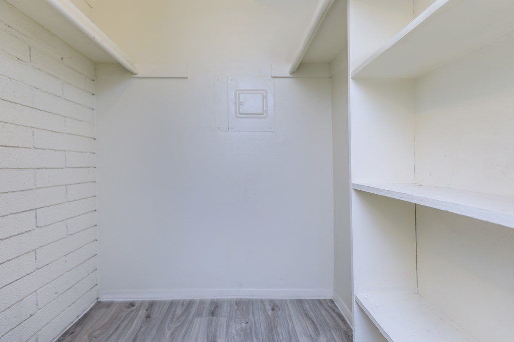 A white wall with a light switch and a wooden floor.