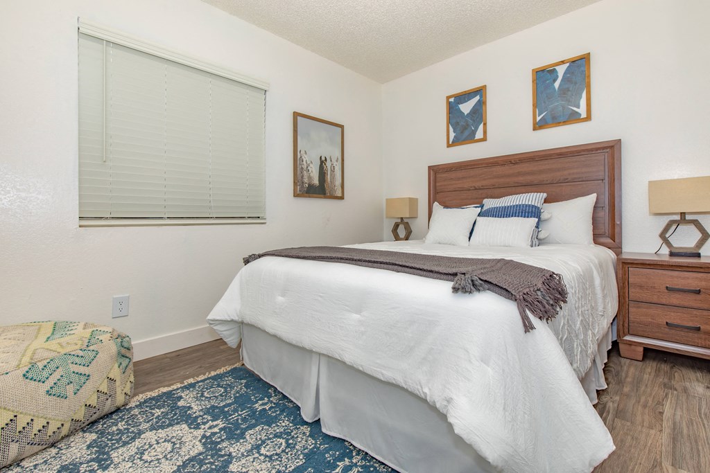 A bedroom with a large bed and a window with blinds.