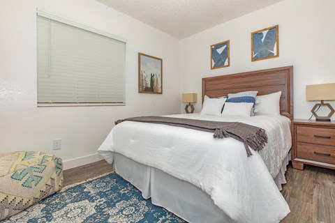 A bedroom with a large bed and a window with blinds.