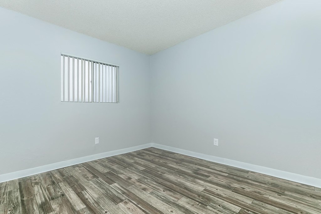 A room with a window and wooden flooring.