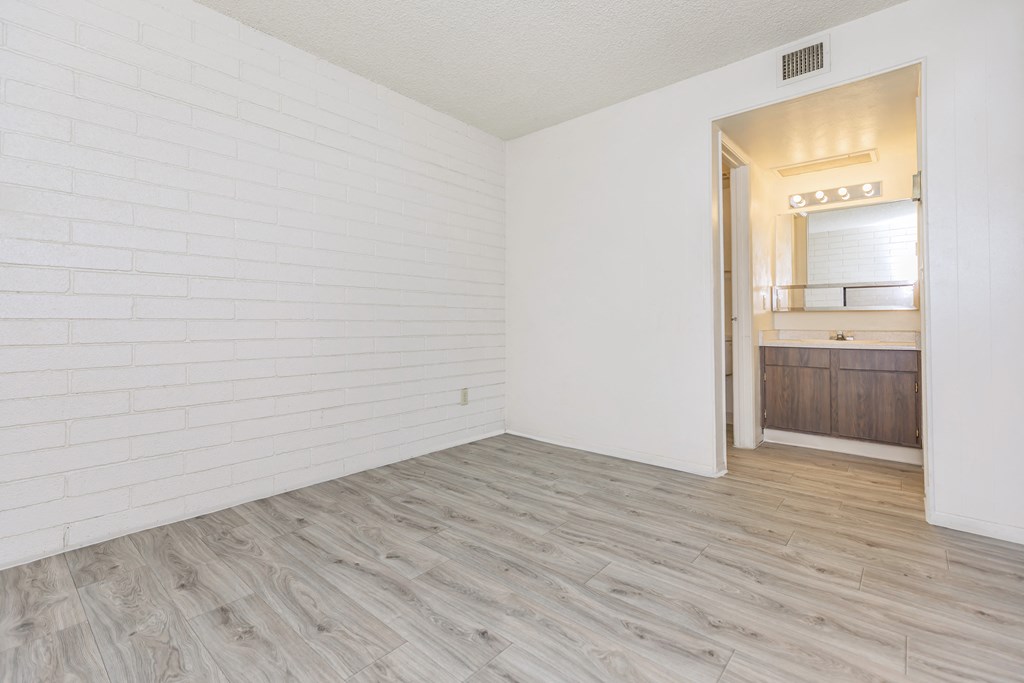 A room with a white brick wall and wooden flooring.