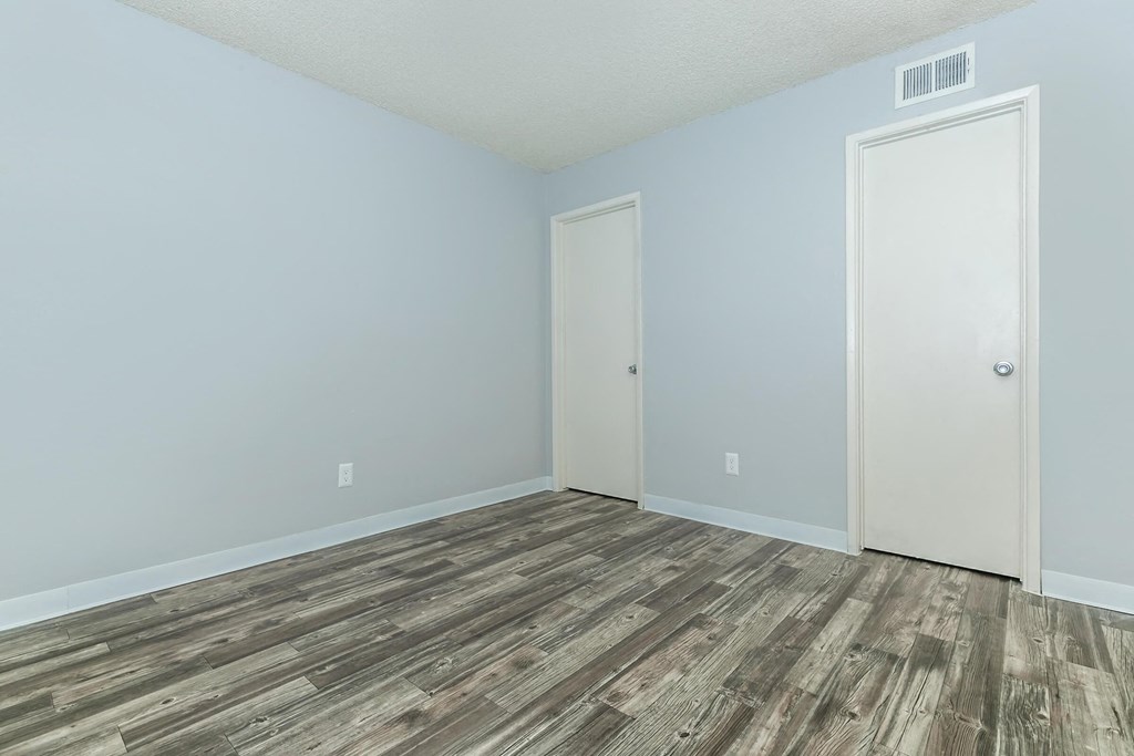 A room with a wooden floor and two doors.