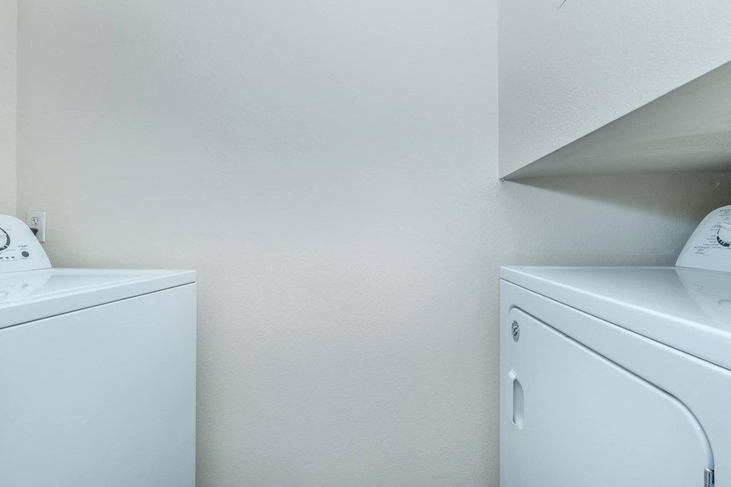 Two white washing machines in a laundry room.