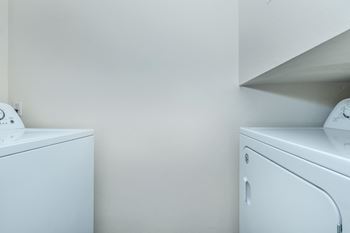 Two white washing machines in a laundry room.