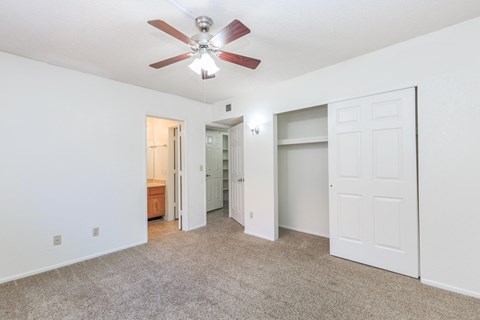A room with a ceiling fan and carpeted floor.